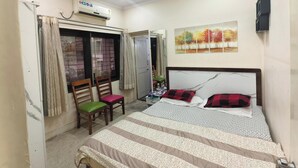 Ein Schlafzimmer mit einem Bett, Deckenventilator, Klimaanlage, einem Fenster mit Vorhängen und einem Gemälde an der Wand.