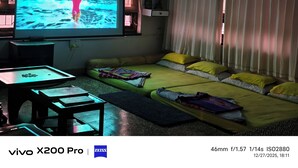 Ein Wohnzimmer mit einem großen Flachbildfernseher, einer Couch, einem kleinen Tisch und einem Projektor.