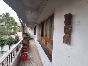 A balcony with potted plants, a wooden door, and a wall-mounted sculpture.