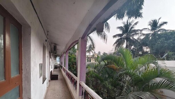 Ein Korridor mit Balkon, Palmen und einer Gebäudefassade.