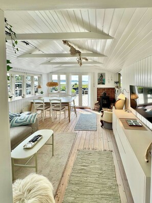 A cozy living room with a dining area, a fireplace, and large windows offering a view.