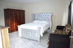 Een slaapkamer met een bed, een kledingkast, een stoel en een bank.