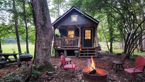 Eine Hütte mit einer Terrasse, einem Feuerkorb und Sitzgelegenheiten im Freien.