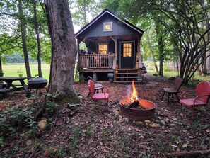 A cabin with a deck, a fire pit, and outdoor seating.