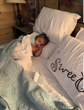 Ein Kind schläft in einem Bett mit einem Kopfkissen mit der Aufschrift 'Sweet'.