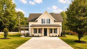 A two-story house with a front porch, a driveway, and a lawn. - Beautiful Brand New Build 3-bedroom house in peaceful Rolesville 2 king bed (Rolesville)