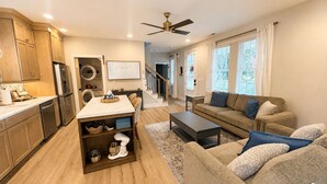 A modern living space with a kitchen, dining area, and a cozy seating area with a sofa and coffee table. - Beautiful Brand New Build 3-bedroom house in peaceful Rolesville 2 king bed (Rolesville)