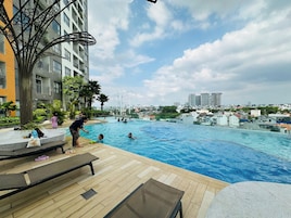 Una piscina con sillones de descanso y vistas a la ciudad.