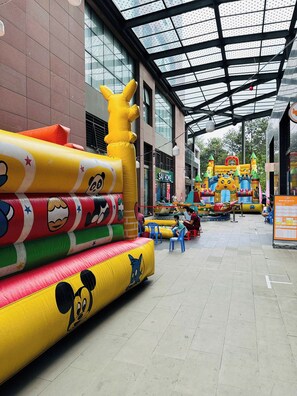 Zona de juegos interior con estructuras hinchables y techo de cristal.