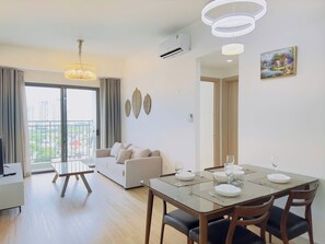 A modern living room with a glass dining table, sofa, and a balcony with a view. - Nice Luxury Apartments The Sun Avenue (Ho Chi Minh City)
