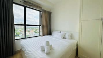 A hotel room with a large window, a bed with white linens, and a wardrobe.