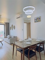 Un comedor moderno con mesa de vidrio, sillas de madera y una araña.