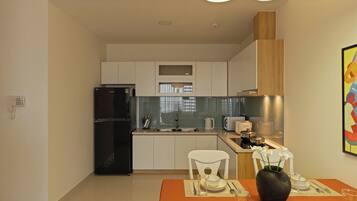 A modern kitchen with a black refrigerator, white cabinets, and a dining area with a table set for two.