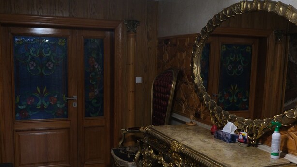 Una habitación con candelabro, espejo decorativo y suelo estampado.