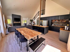 Une cuisine moderne avec des meubles de couleur sombre, un îlot central en bois et un four encastré.