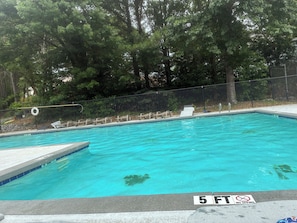 Une piscine dont la profondeur maximale est indiquée à 1,5 mètre, entourée d’arbres et délimitée par une clôture.