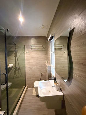 Ein modernes Badezimmer mit einer Duschkabine, einem weißen Waschbecken und einem großen Spiegel.