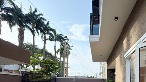 A courtyard with a paved floor, a gated entrance, a potted plant, and a building with a brick facade. - Citiscape Apartment (Ikeja)