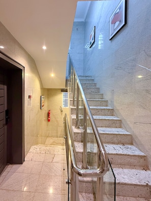 Eine Marmortreppe mit Metallgeländern, die zu einer oberen Etage führt.