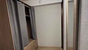 Een kamer met een houten garderobe, een spiegel en een lamp aan het plafond.
