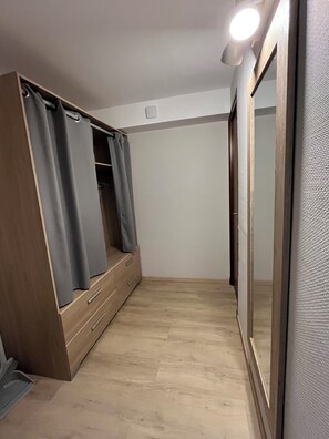 A room with a wooden wardrobe, a mirror, and a light fixture on the ceiling.