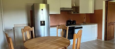 Una cocina compacta con una mesa y sillas, un refrigerador y una cafetera.