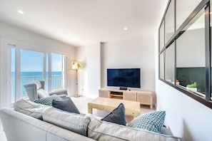 A modern living room with a sofa, a coffee table, a TV, and a balcony with a view. - LXR Nice 3-Bedroom Oceanfront (Fuengirola)