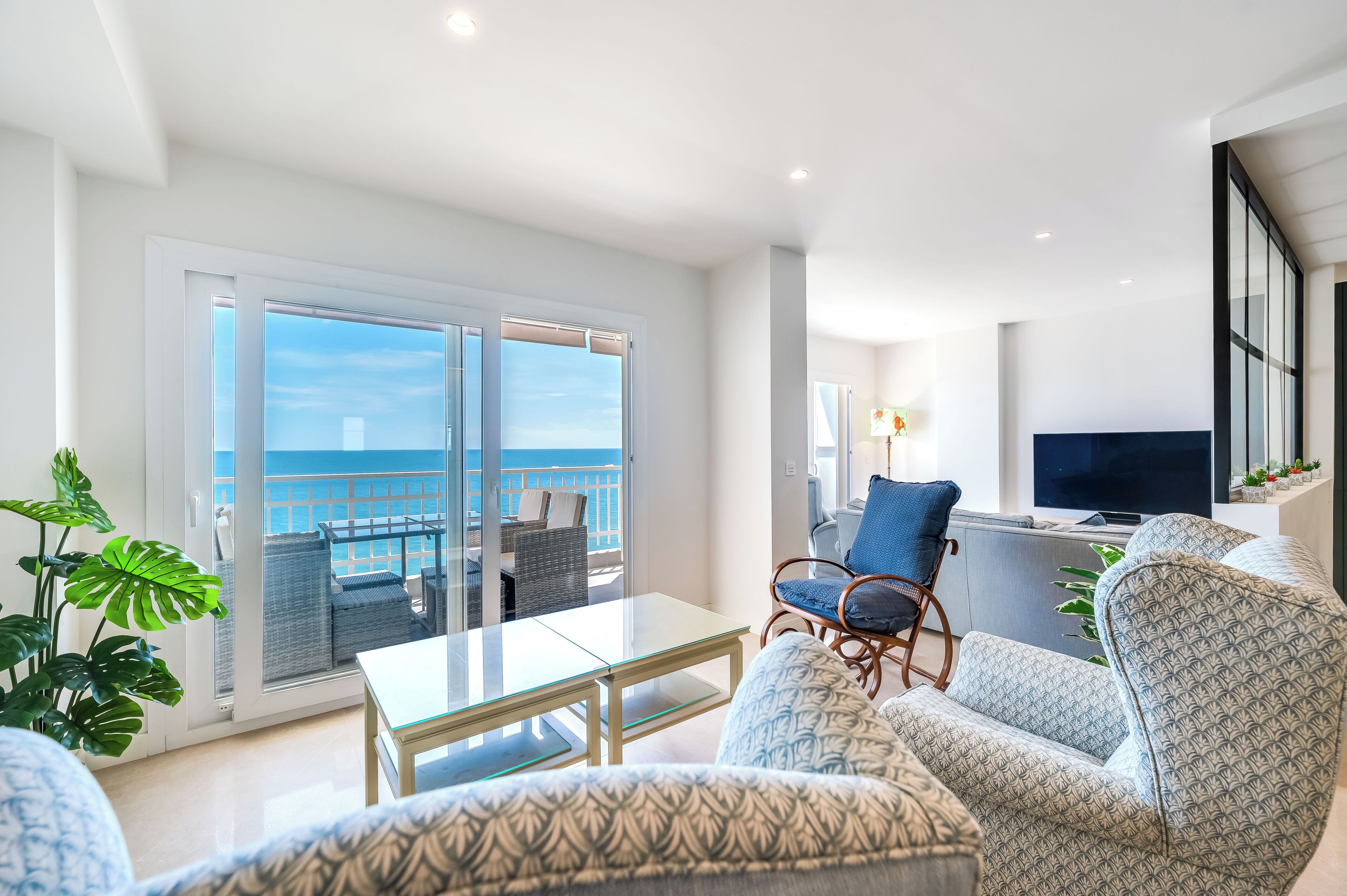 A modern living room with a balcony, a TV, and a seating area.
