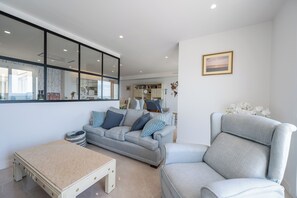 A modern living room with a sofa, armchair, and a small table. - LXR Nice 3-Bedroom Apartment Right on the Waterfront (Fuengirola)