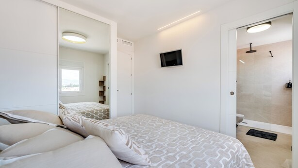 A bedroom with a bed, a mirror, a TV, and a shower area. - LXR Nice 3-Bedroom Oceanfront (Fuengirola)