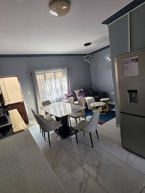 Una cocina moderna con comedor, refrigerador y ventana con cortinas.