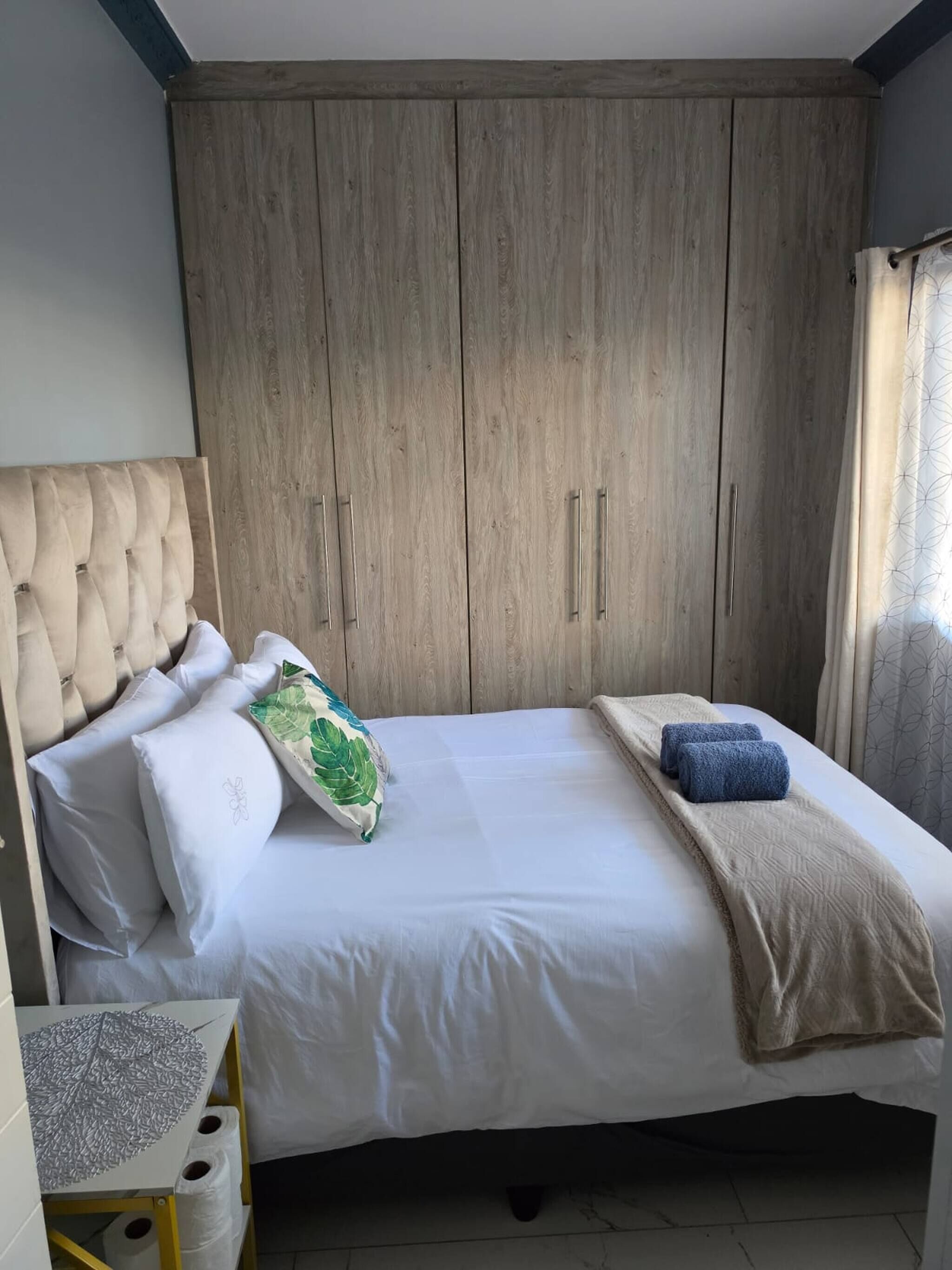 Un dormitorio con cama, un armario de madera y una mesita con un adorno.