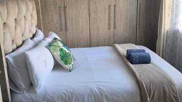 Un dormitorio con cama, un armario de madera y una mesita con un adorno.