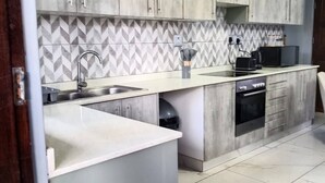 Una cocina moderna con gabinetes grises, un salpicadero de baldosas en espiga, horno empotrado y un lavabo.