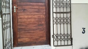 Una puerta de madera con una reja metálica, el número '3' en la puerta y un pequeño ventanal encima de la reja.