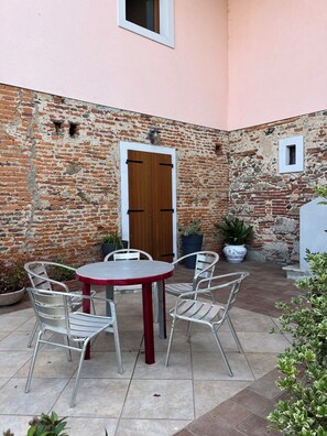 A brick wall with a wooden door, a round table with chairs, and potted plants. - A Getaway in Nature: Lakes & Golf (Bogogno)