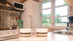 Una cocina con estufa, microondas y ventanas amplias.