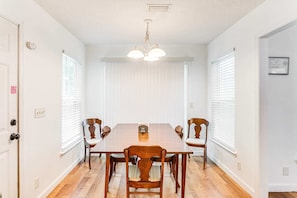 Ein Esszimmer mit Holztisch und -stühlen, weißen Wänden und einer Deckenleuchte.
