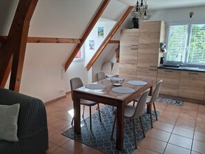 A dining area with a wooden table, chairs, and a kitchen in the background.