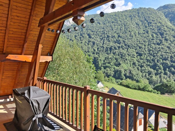 A wooden balcony with a view of a forested mountain.