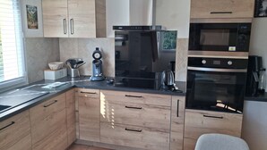 A modern kitchen with wooden cabinets, a built-in oven, a coffee maker, and a kettle.