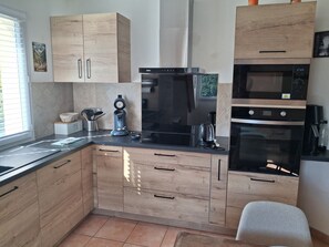 Eine moderne Küche mit Holzausstattung, integriertem Backofen, Kaffeemaschine und Wasserkocher.