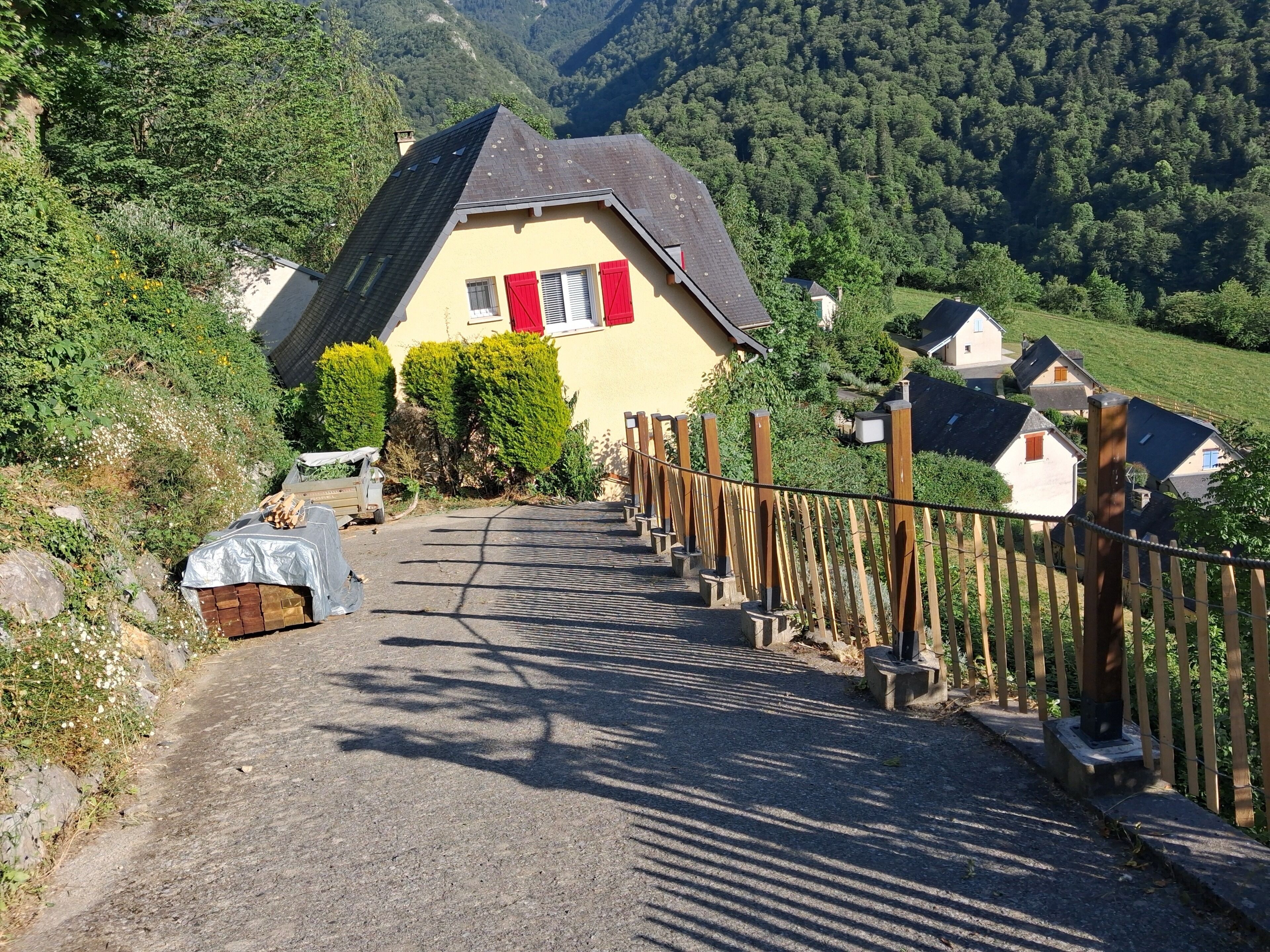 A rural road leading to a house with a sloped roof and red shutters.