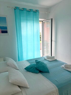 Ein Zimmer mit einem Bett, einem Fenster mit Aussicht und einem Vorhang.