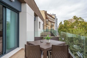 A balcony with a table and chairs, a glass railing, and a view of surrounding buildings. - LXR Meninas 2-Bedroom Apartment Near the Sea (Fuengirola)