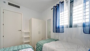 A bedroom with two beds, a wardrobe, a mirror, and a window with curtains. - LXR Meninas 2-Bedroom Apartment Near the Sea (Fuengirola)