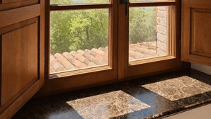 A room with a large wooden door leading to a view of a landscape with trees and a stone wall. - Villa Santa Maria dell'Olmo (MORESCO)
