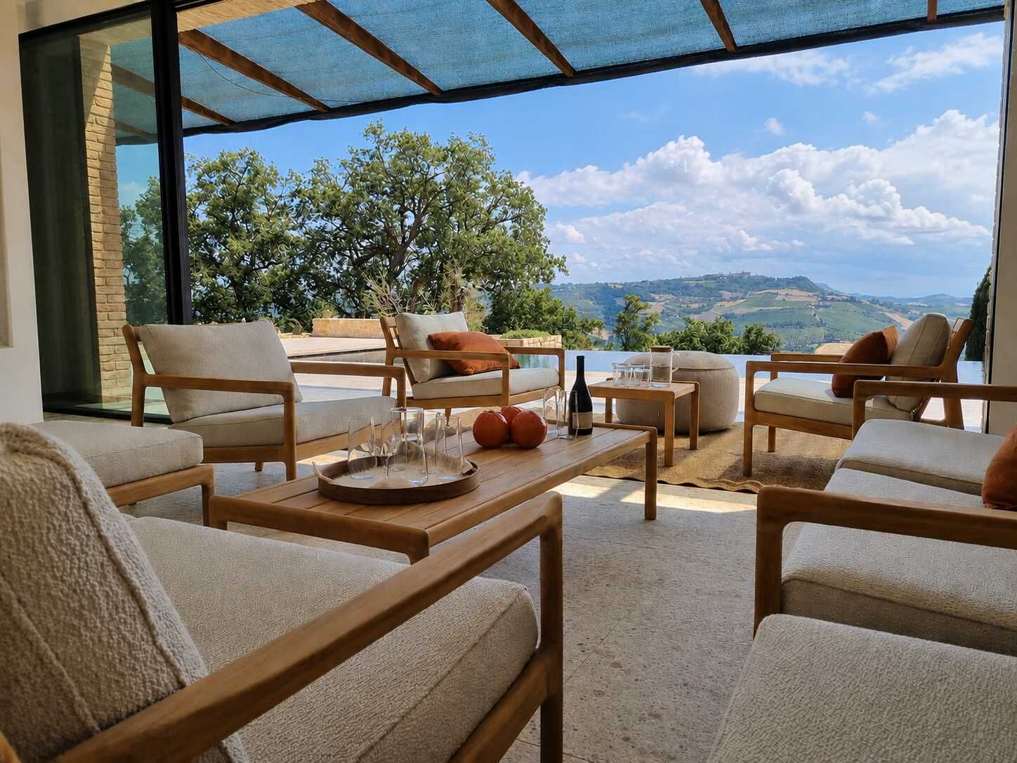 A sunlit outdoor seating area with wooden furniture and a view of the countryside.