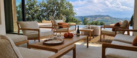 A sunlit outdoor seating area with wooden furniture and a view of the countryside.