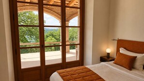 A bedroom with a bed, a nightstand, and a view through a glass door to an outdoor area. - Villa Santa Maria dell'Olmo (MORESCO)